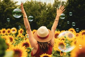 Woman excited raising her hands in the air in a field of abundance of sunflowers